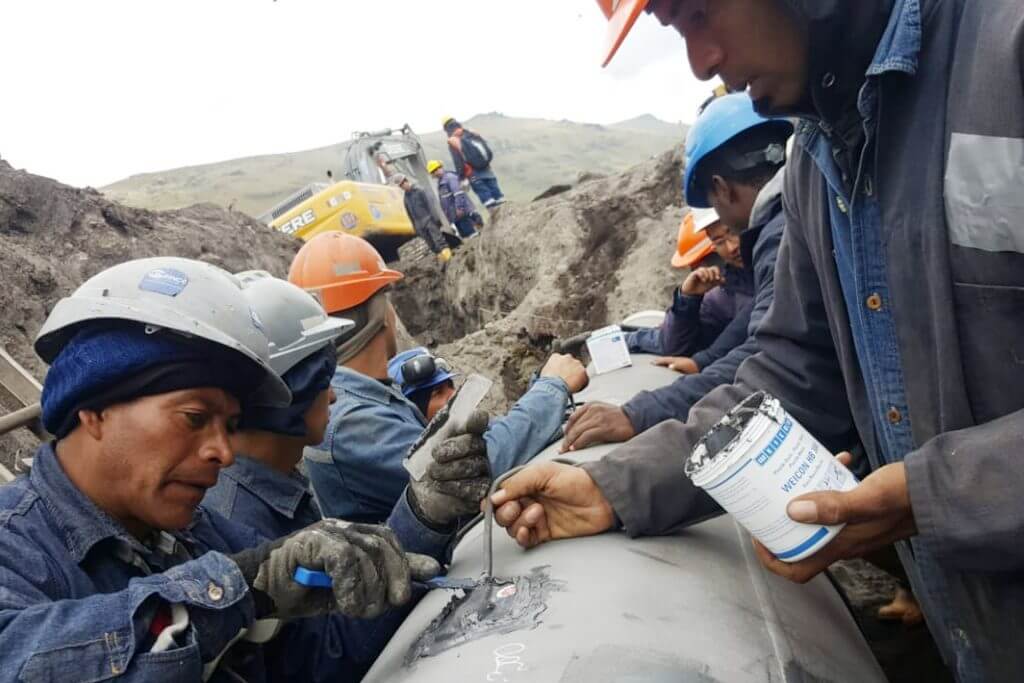 Mehrere Männer reparieren eine Pipeline mit Klebstoff und Spachtel